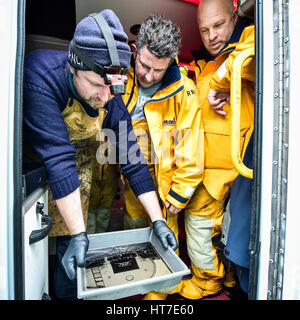 Fotograf Jack Lowe, Platte zeigt Rettungsboot-Crews ein viktorianischen Glas Platte Foto, das er in seine mobile Dunkelkammer, einem stillgelegten NHS Krankenwagen entwickelt, die er nutzt, um Reisen mit seinen viktorianischen Glas Kamera in seiner Mission, alle 237 RNLI-Rettungsboot-Stationen in Großbritannien und Irland für das The Lifeboat Station Projekt zu erfassen. Stockfoto