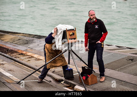 Fotograf Jack Lowe, und sein Assistent Ian Henderson, (rechts) Einrichten einer viktorianischen Glas Plattenkamera auf der Slipanlage in Padstow RNLI Station vor dem Fotografieren der Crew als Teil seiner Mission, alle 237 RNLI-Rettungsboot-Stationen in Großbritannien und Irland für das The Lifeboat Station Projekt zu erfassen. Stockfoto