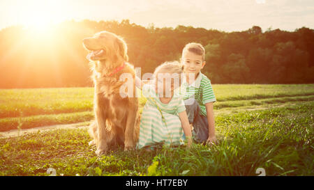 Entzückende Bruder und Schwester, die das Spiel mit Hund Stockfoto