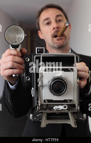 Foto eines Retro-40er Stil Fotografen fotografieren mit einer alten 4 x 6-Kamera.  Fotograf unscharf und Kamera im Fokus. Stockfoto