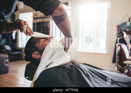 Friseur für Gesicht des Clients mit Handtuch. Mann besuchen Friseur. Stockfoto