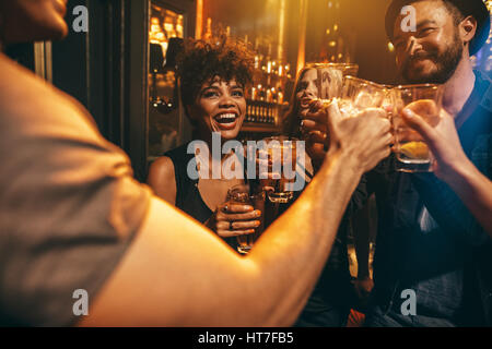 Gruppe von Jugendlichen, die Getränke in der Diskothek toasten. Junge Männer und Frauen, die Spaß an der Lounge Bar. Stockfoto