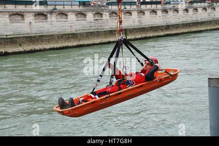 Ein Feuerwehrmann der Eliteeinheit sofort (Rettung unter gefährlichen Bedingungen) ist in einer trage über den Fluss Seine während der Ausbildung in Paris Winde. Stockfoto