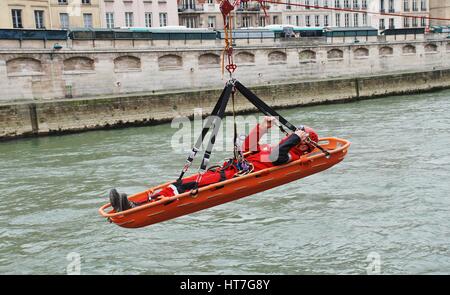 Ein Feuerwehrmann der Eliteeinheit sofort (Rettung unter gefährlichen Bedingungen) ist in einer trage über den Fluss Seine während der Ausbildung in Paris Winde. Stockfoto