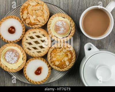 Teller mit sortierten individuelle Dessert Kuchen oder Torten mit einer Kanne Tee Stockfoto