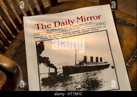 TITANIC DISASTER ZEITUNG Daily Mirror April 16. 1912, RMS Titanic Schiff Disaster News Schlagzeilen auf altmodischem bosuns Stuhl beleuchtet durch Schacht der Fensterbeleuchtung Stockfoto