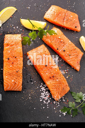 Frischer Lachs mit Kräutern und Gewürzen fertig zum Backen auf Stein Hintergrund Stockfoto