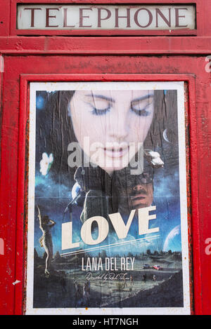 Werbe-Plakat für "Love" ein Lied der amerikanischen Sängerin Lana Del Rey auf eine traditionelle britische Telefonzelle. Stockfoto