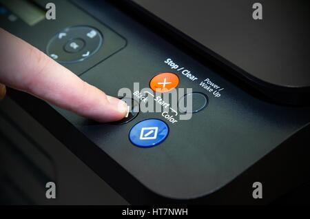 Mann mit Finger auf die Schaltfläche "Start" von Laser-Drucker Stockfoto