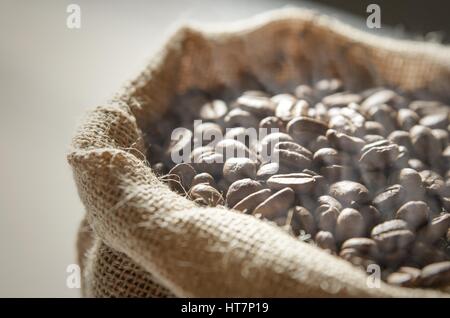 Kaffeebohnen in Jute-Tasche auf Holztisch hautnah Stockfoto