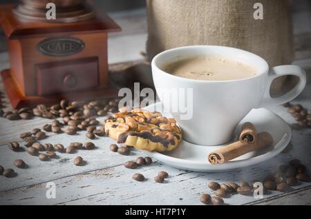 Kaffee, gerösteten Bohnen, Mühle, Mühle und Cookies mit Nüssen auf hölzernen Hintergrund Stockfoto