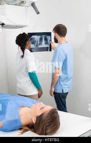 Männliche und weibliche Radiologen Analyse Röntgen mit Frau im Vordergrund im Krankenhaus liegen Stockfoto