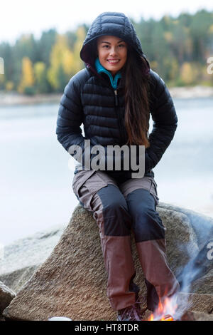 Porträt der glückliche junge Frau trägt Winterjacke während camping am See Stockfoto