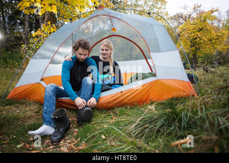 Junge Frau betrachten Mann trägt Wanderschuh im Zelt beim camping Stockfoto