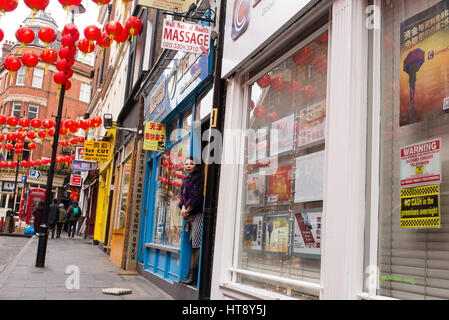 Chinesische Frau vor chinesischen Massagesalon in Chinatown, London, UK Stockfoto