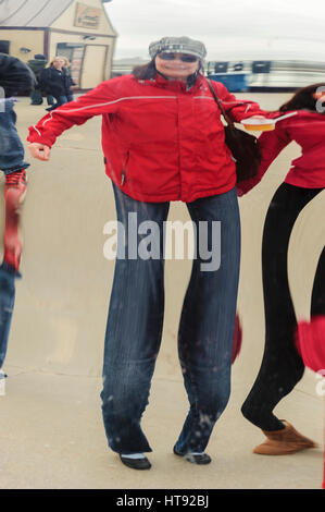 Das Bild einer Frau mittleren Alters mit roter Jacke spiegelt sich auf der Oberfläche eines verzerrenden Spiegels am Navy Pier in Chicago, Illinois. Stockfoto