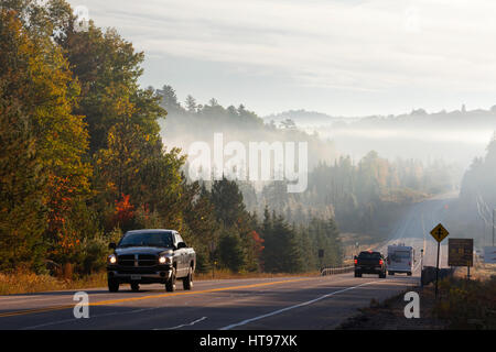 LKW und ein Wohnmobil van Drving entlang Highway 60 mit Nebel in niedrig gelegenen Gebieten in Algonquin Provincial Park, Ontario, Kanada. Stockfoto