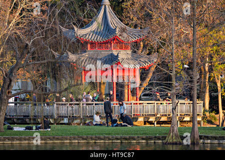 Menschen Picknick rund um den roten chinesischen Ting-Pavillon am Lake Eola Park in Orlando, Florida. Lake Eola Park ist gelegen im Herzen von Downtown Orlando und Heimat der Walt-Disney-Amphitheater. Stockfoto