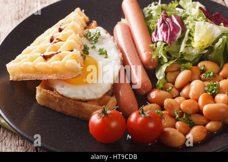 Frühstück: Gebratenes Ei, Waffeln, Würstchen, Bohnen und Salat Nahaufnahme auf einer Platte. horizontale Stockfoto