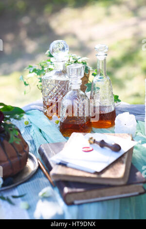 Cocolate Kuchen verziert mit Blumen und drei Whiskey Dekanter gegen einen hellgrauen Hintergrund mit Textfreiraum Stockfoto