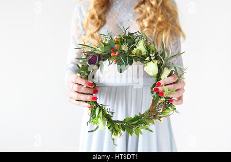 Braut mit Frühling Blumen Kranz in ihren Händen auf einem grauen Hintergrund isoliert. Stockfoto