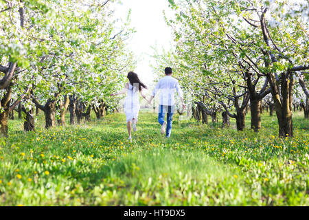 Junges Paar in der Liebe, die im Frühling blühen Garten laufen. Glück und Liebe Konzept Stockfoto