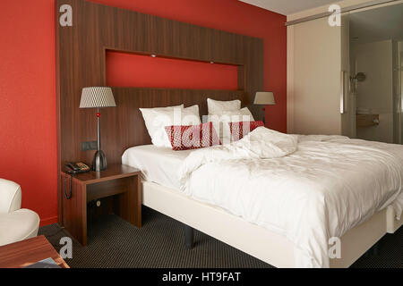 Moderne Hotelzimmer mit roten Wand und Holzbett Umwandlung. Stockfoto