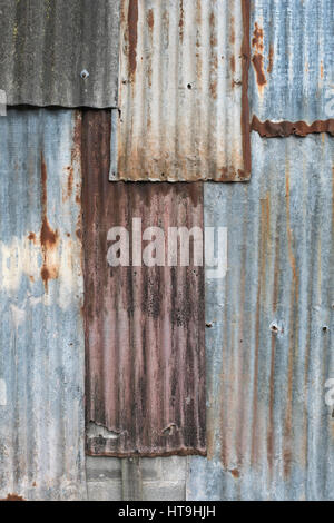 Überlagerte Abschnitte aus rostfreiem verzinktem/verzinktem Stahlblech. Verwitterte Metallstruktur, gewelltes Stahlblech. Stockfoto