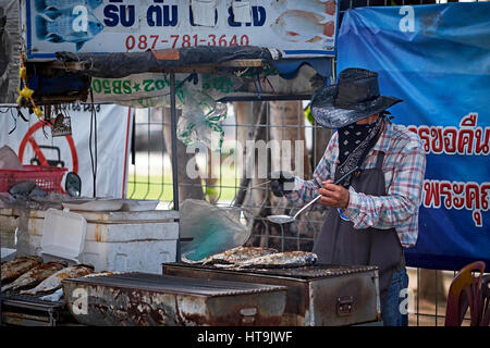 Thailand Street Food Verkäufer Kochen in seinem Fischstand und trägt eine Gesichtsmaske. Thailand Südostasien Stockfoto