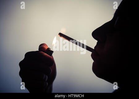 Silhouette einer Frau, die aufleuchten einer Zigarette. Stockfoto