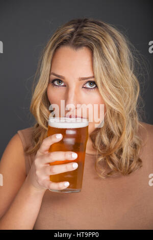 Schöne junge Frau mit einem Drink für ein Pint Lager. Stockfoto