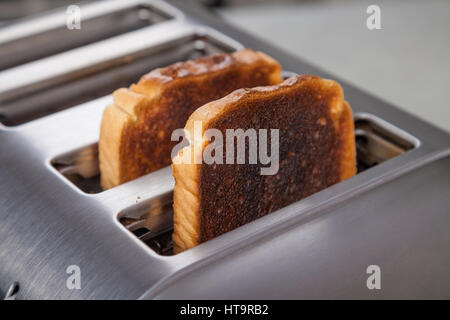 Zwei Scheiben von verbranntem Toast in einem Metall Toaster. Stockfoto