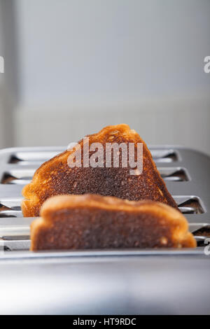 Zwei Scheiben von verbranntem Toast in einem Metall Toaster. Stockfoto