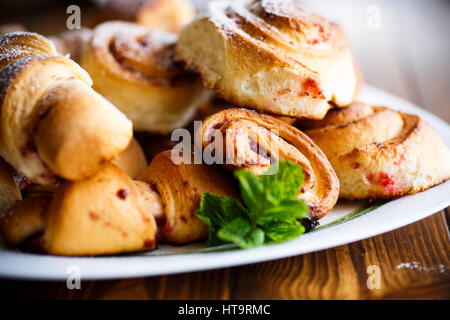 Süße Brötchen mit Marmelade auf einem Holztisch Stockfoto