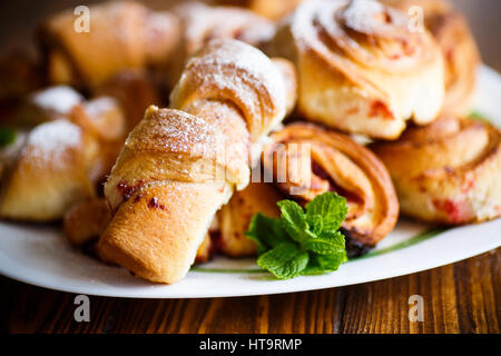 Süße Brötchen mit Marmelade auf einem Holztisch Stockfoto