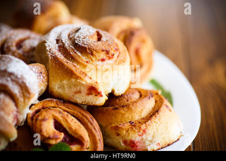 Süße Brötchen mit Marmelade auf einem Holztisch Stockfoto