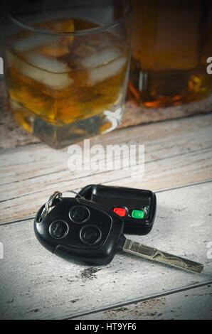 Autoschlüssel, Glas Whiskey im Hintergrund. Fahren unter Alkoholeinfluss Stockfoto