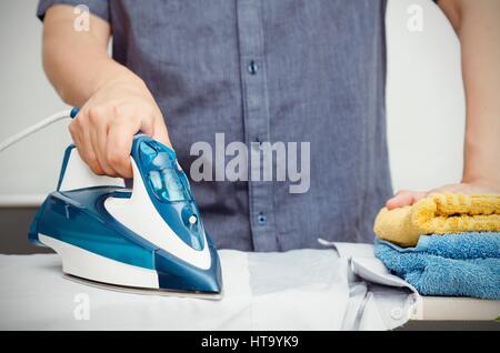 Man bügelt Kleider auf Bügelbrett mit dampfenden blau Eisen Stockfoto