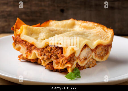 Hausgemachte italienische Lasagne Bolognese auf weißen Teller mit Basilikum Stockfoto