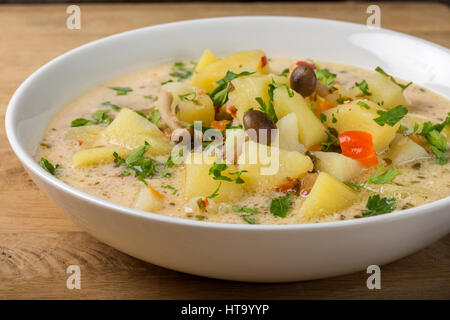 Kartoffel-Suppe mit Pilzen und saurer Sahne in weiße Schüssel auf Holz Stockfoto
