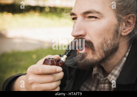 Schweren asiatischen bärtigen Jüngling Pfeife im Sommerpark, Nahaufnahme portrait Stockfoto