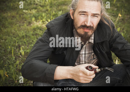 Junge asiatische bärtiger Mann rauchen Pfeife im Sommerpark, Closeup portrait Stockfoto