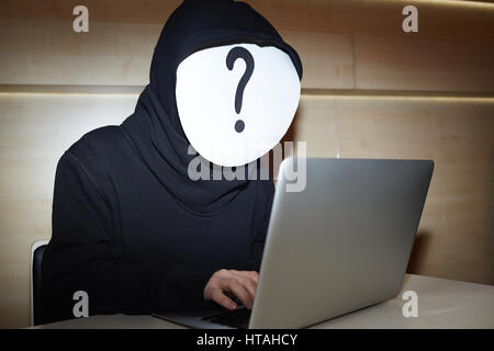 Taille-Up Portrait von anonymer Hacker in schwarzer Hoodie und weiße Maske mit Fragezeichen, die versuchen, persönliche Daten von Laptop zu stehlen Stockfoto