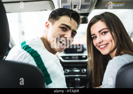 Attraktives Paar wählt ein neues Auto im Showroom, Auto-Kauf und Erfolg-Konzept, im Auto zu sitzen Stockfoto