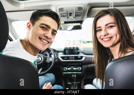 Attraktives Paar wählt ein neues Auto im Showroom, Auto-Kauf und Erfolg-Konzept, im Auto zu sitzen Stockfoto