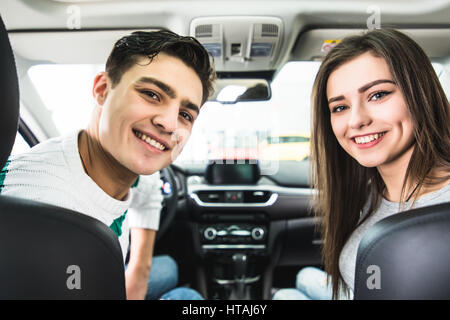 Attraktives Paar wählt ein neues Auto im Showroom, Auto-Kauf und Erfolg-Konzept, im Auto zu sitzen Stockfoto