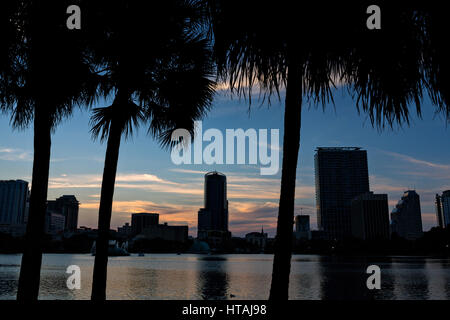 Skyline-Blick über Lake Eola und Palmen Bäume bei Sonnenuntergang in Orlando, Florida. Lake Eola Park ist gelegen im Herzen von Downtown Orlando und Heimat der Walt-Disney-Amphitheater. Stockfoto