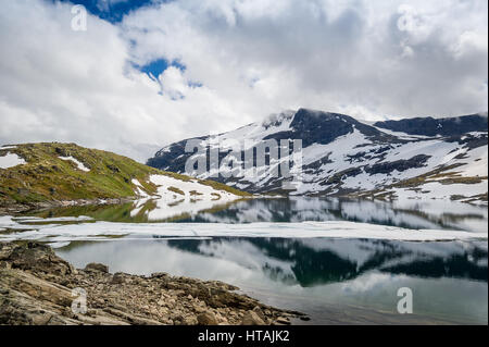 Grüne Hügel, schneebedeckten Felsen und Bergsee - malerische Landschaften des berühmten verschneiten Straße 55, Lom, Norwegen. Stockfoto