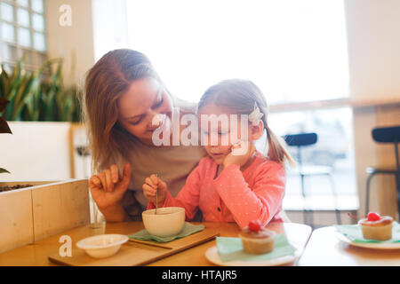 Entzückende Mädchen essen Dessert mit ihrer Mutter in der Nähe von Stockfoto