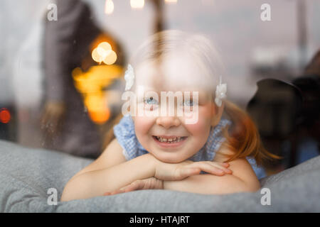 Niedliche kleine Mädchen Blick durch Fenster Stockfoto